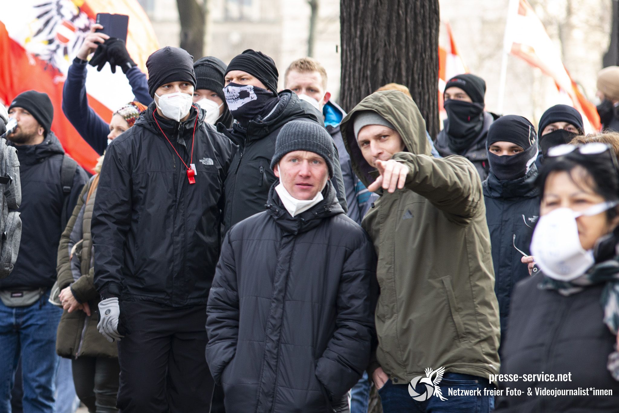 Mit FFP2-Masken vermummte Personen, die auf einen Journalisten zeigen am Wiener Ring.