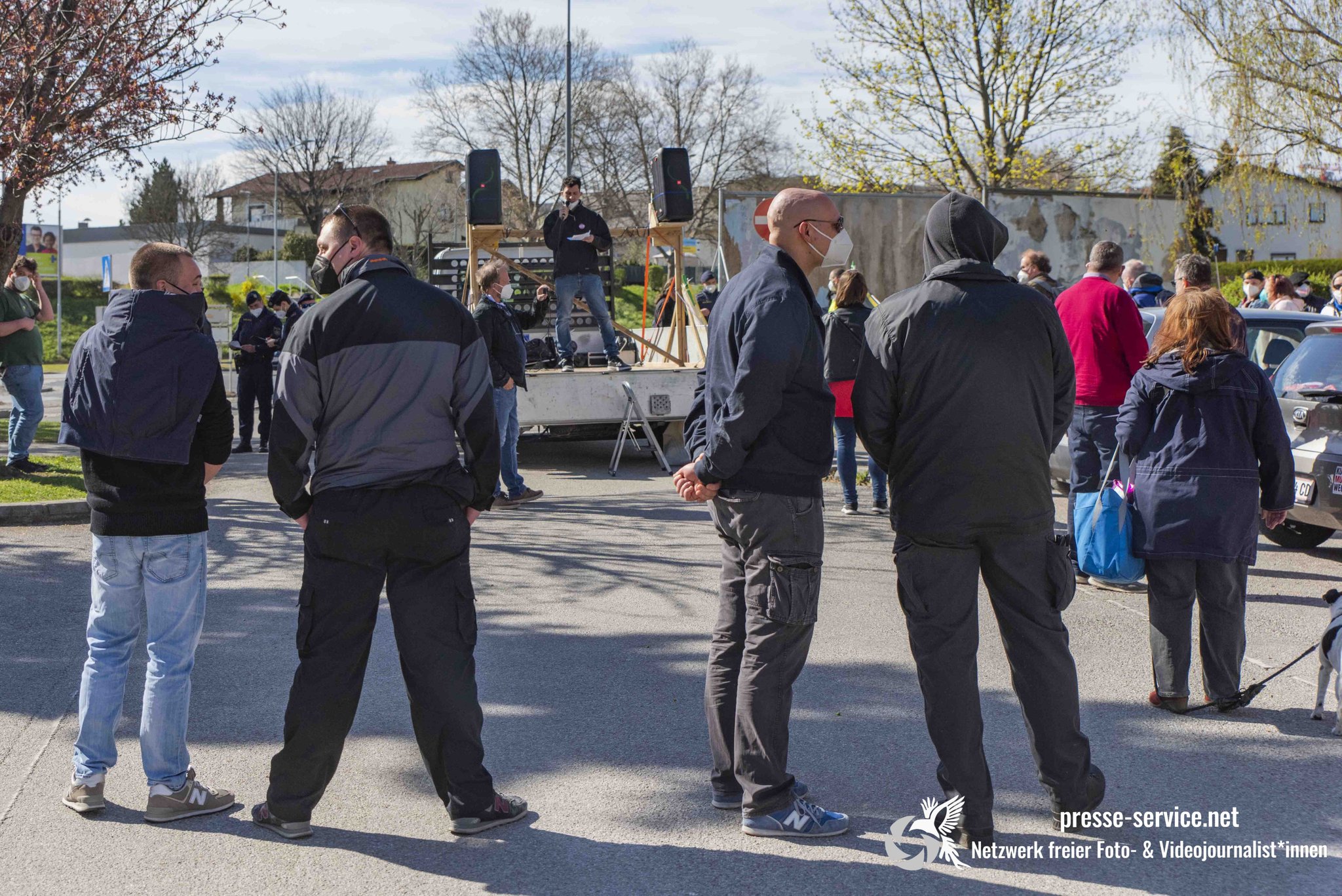 Mehrere Neonazis in Eisenstadt vor einem Kreisverkehr, im Hintergrund ein kleiner Transporterr.